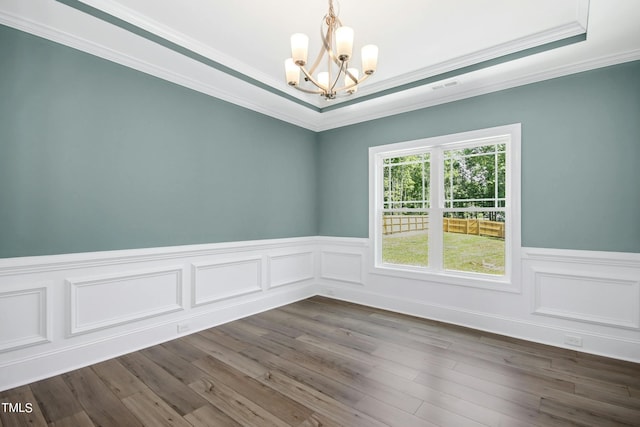 empty room featuring ornamental molding, a raised ceiling, dark wood-type flooring, and a notable chandelier