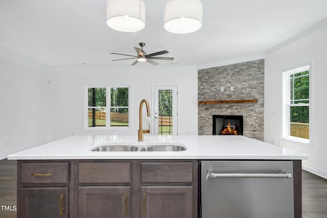 kitchen featuring dishwasher, a stone fireplace, sink, crown molding, and dark hardwood / wood-style flooring