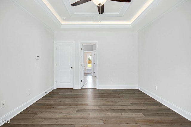 empty room with a raised ceiling, ceiling fan, and dark hardwood / wood-style floors