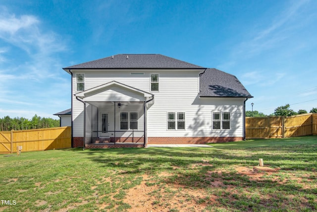 rear view of property with a sunroom, ceiling fan, and a yard