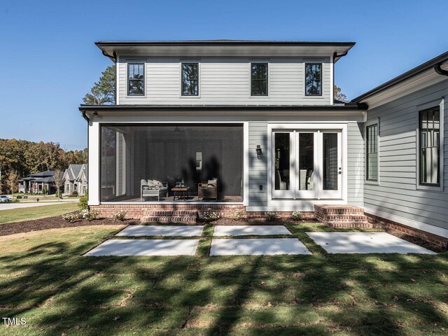 rear view of house featuring a yard, a sunroom, and french doors