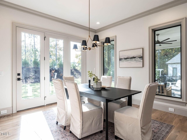 dining space with crown molding, hardwood / wood-style flooring, and ceiling fan with notable chandelier