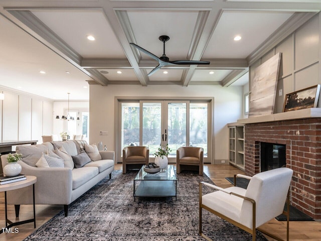 living room featuring a fireplace, hardwood / wood-style floors, coffered ceiling, beamed ceiling, and ornamental molding