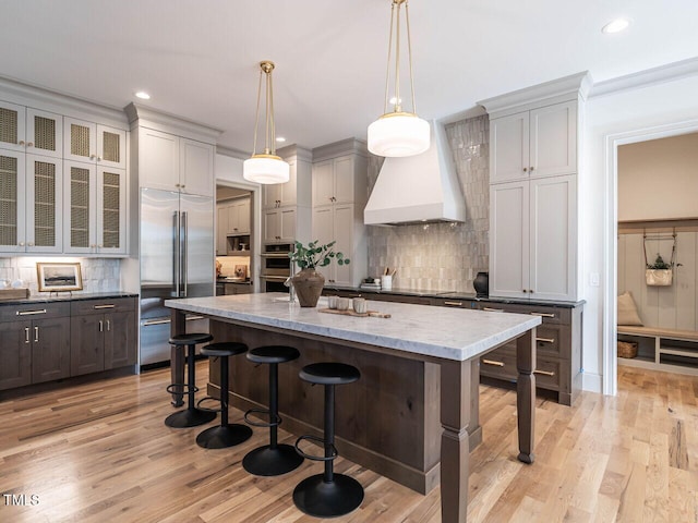 kitchen featuring decorative backsplash, a kitchen island, appliances with stainless steel finishes, a kitchen breakfast bar, and light hardwood / wood-style flooring