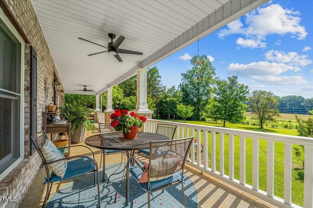 wooden deck with a lawn, a ceiling fan, covered porch, and outdoor dining area