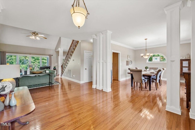 living room featuring baseboards, decorative columns, light wood finished floors, and ceiling fan with notable chandelier
