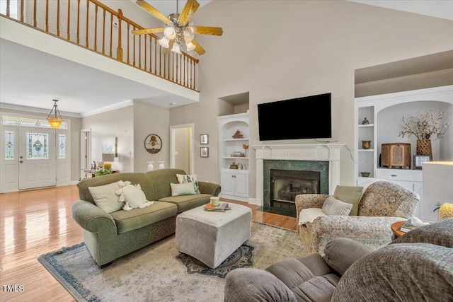 living room featuring built in features, wood finished floors, and a towering ceiling