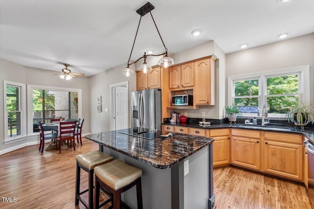 kitchen with stainless steel appliances, a breakfast bar, a sink, and light wood finished floors