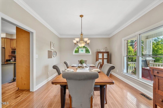 dining area with an inviting chandelier, light wood-style flooring, crown molding, and baseboards