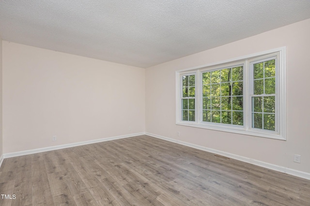 unfurnished room with a textured ceiling and light hardwood / wood-style flooring