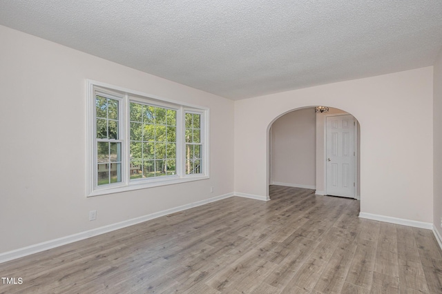 empty room with a textured ceiling and light wood-type flooring