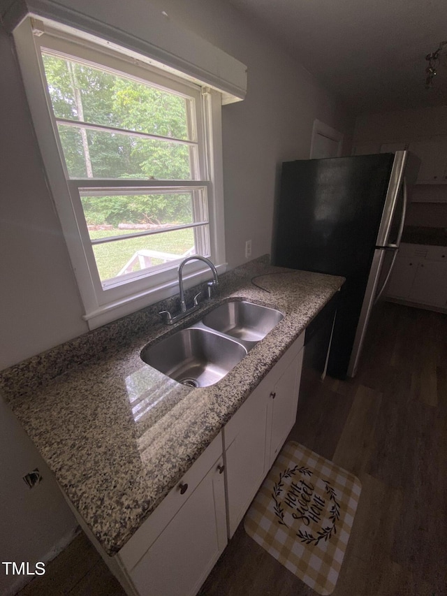 kitchen featuring sink, stainless steel fridge, light stone counters, dark hardwood / wood-style flooring, and white cabinetry