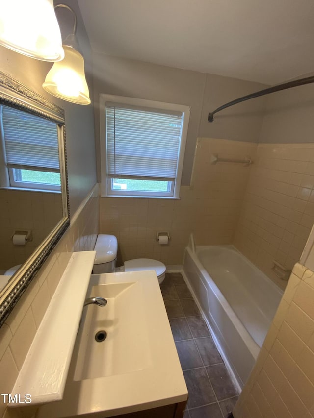 full bathroom with tile patterned floors, a wealth of natural light, tile walls, and toilet