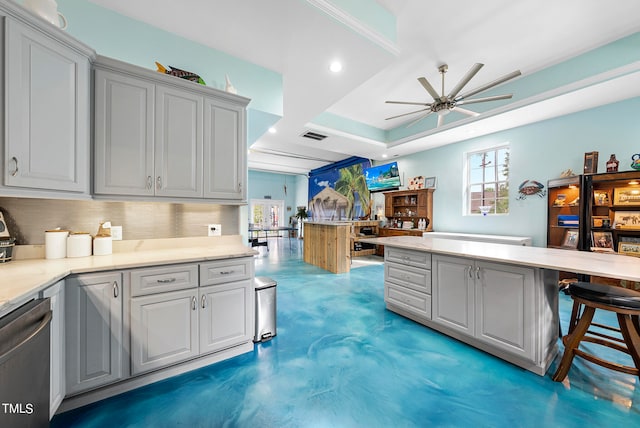 kitchen featuring ceiling fan, stainless steel dishwasher, a raised ceiling, gray cabinets, and backsplash