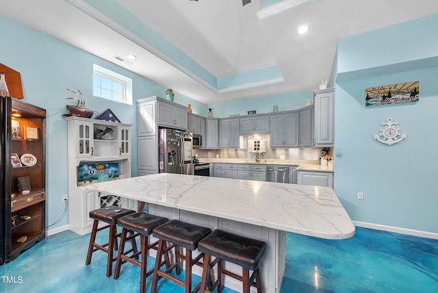 kitchen with light stone countertops, backsplash, gray cabinetry, and stainless steel appliances