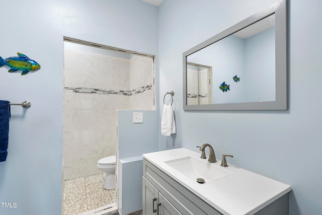 bathroom featuring tile flooring, tiled shower, oversized vanity, and toilet