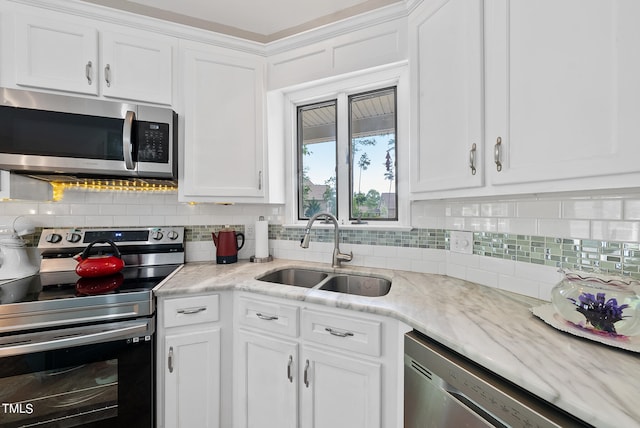 kitchen with appliances with stainless steel finishes, sink, white cabinets, and backsplash