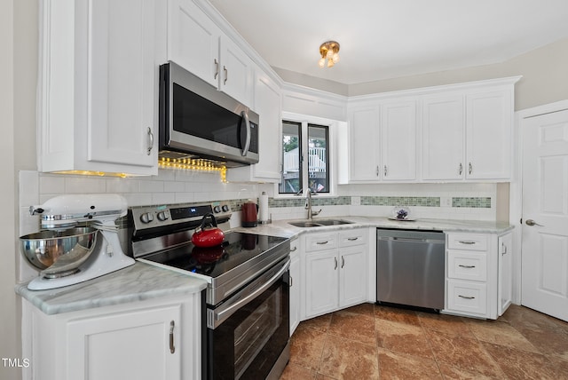 kitchen featuring stainless steel appliances, sink, white cabinetry, and backsplash