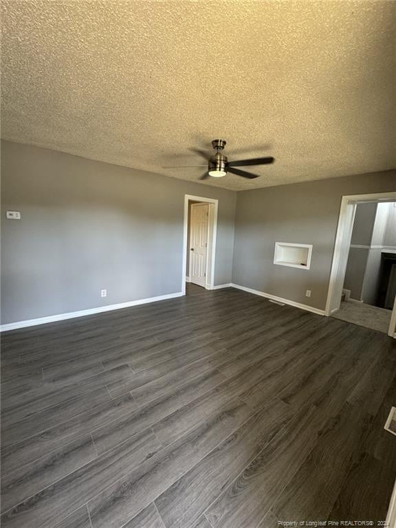 empty room featuring a fireplace, a textured ceiling, dark hardwood / wood-style flooring, and ceiling fan