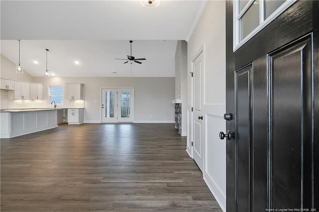 unfurnished living room featuring sink, vaulted ceiling, ornamental molding, dark hardwood / wood-style floors, and ceiling fan