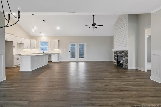 unfurnished living room featuring dark wood-type flooring, sink, high vaulted ceiling, ceiling fan, and a fireplace