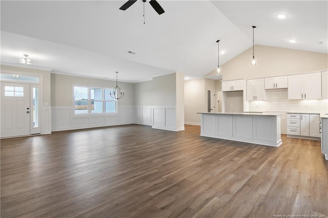 unfurnished living room featuring hardwood / wood-style floors, ceiling fan with notable chandelier, and high vaulted ceiling