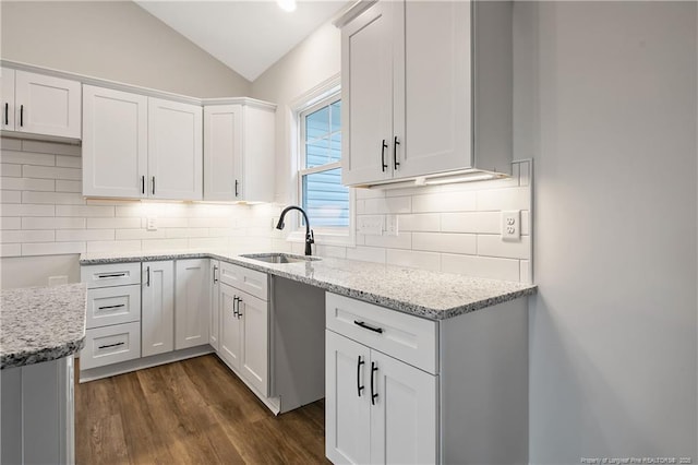 kitchen featuring vaulted ceiling, dark hardwood / wood-style floors, sink, white cabinets, and light stone counters