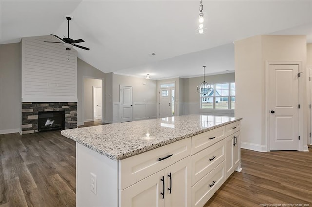 kitchen with light stone countertops, a center island, hanging light fixtures, and white cabinets