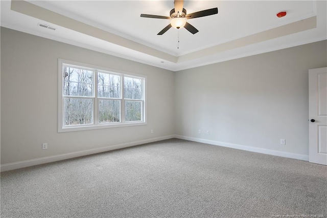 carpeted empty room with a raised ceiling and ceiling fan