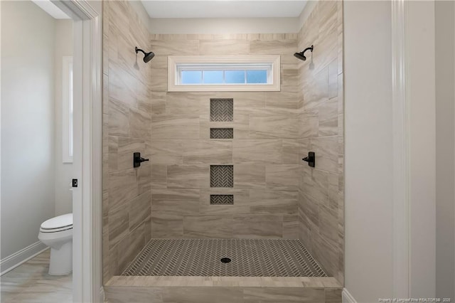 bathroom with a tile shower and toilet