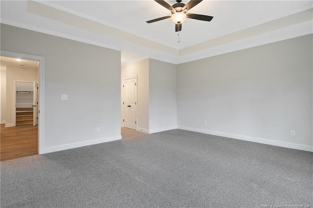 empty room featuring crown molding, ceiling fan, a raised ceiling, and carpet floors