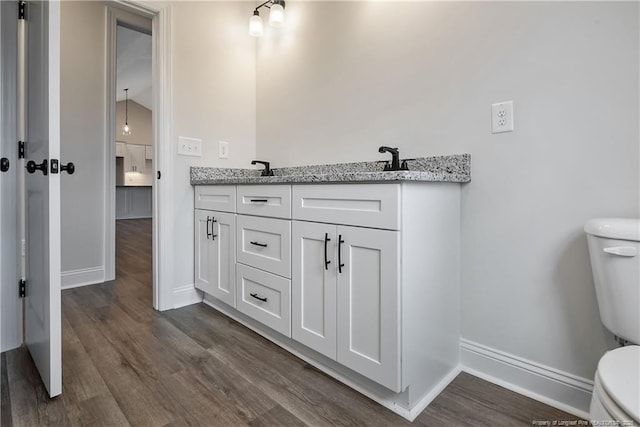 bathroom with vanity, toilet, and hardwood / wood-style floors