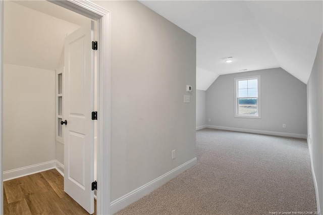 bonus room featuring vaulted ceiling and light colored carpet