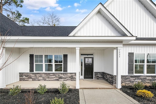 1237 Joe Hall Rd, Hope Mills, NC 28348 - doorway to property with stone siding, a porch, roof with shingles, and board and batten siding