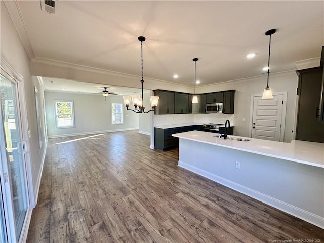 kitchen featuring dark wood-type flooring, appliances with stainless steel finishes, decorative light fixtures, and sink