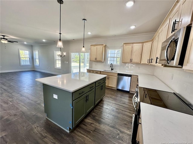 kitchen featuring sink, appliances with stainless steel finishes, a center island, green cabinetry, and decorative light fixtures