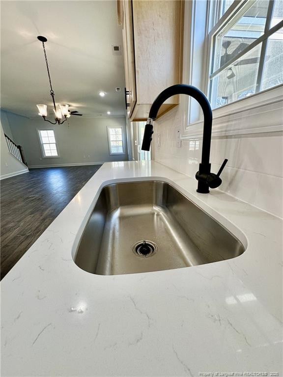 interior details with an inviting chandelier, sink, pendant lighting, and light stone counters