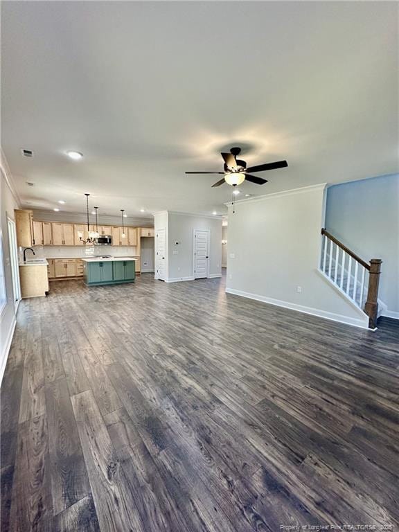 unfurnished living room featuring ornamental molding, dark wood-type flooring, sink, and ceiling fan