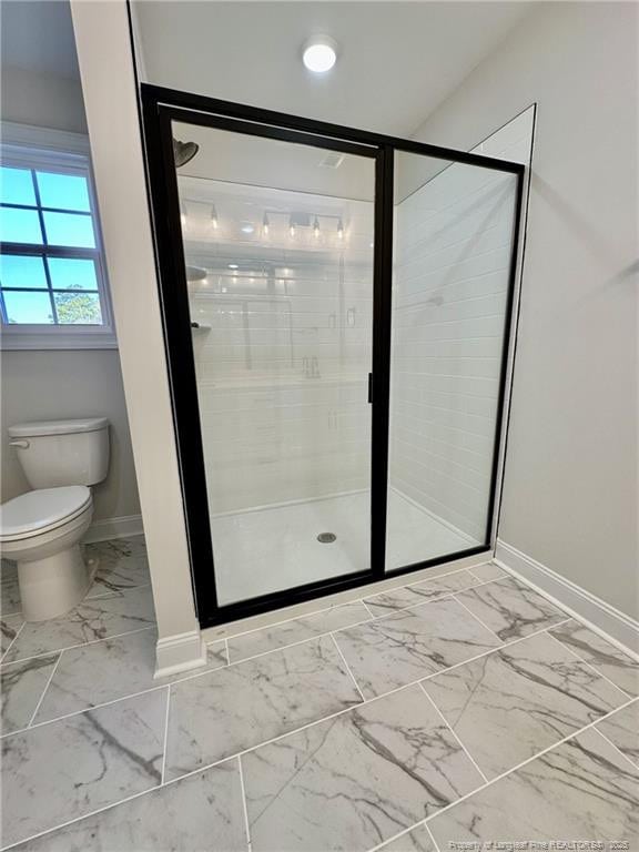 bathroom featuring a shower with shower door and toilet