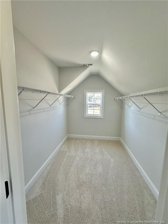 walk in closet featuring vaulted ceiling and light carpet