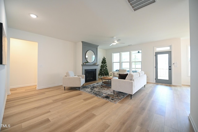 living room featuring a large fireplace, ceiling fan, and light hardwood / wood-style floors