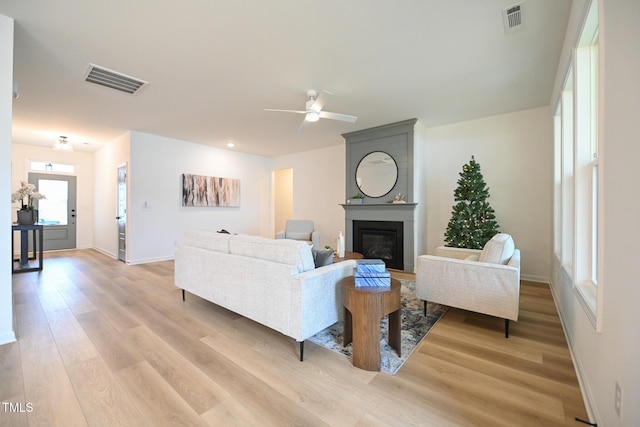 living room with ceiling fan, a fireplace, and light hardwood / wood-style floors