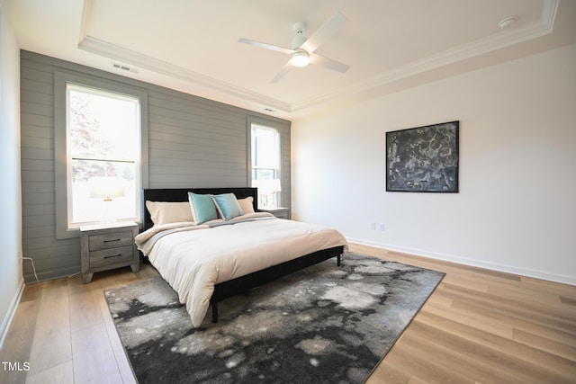 bedroom with hardwood / wood-style floors, ceiling fan, a tray ceiling, and multiple windows