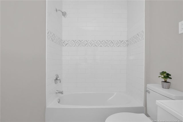 bathroom with toilet and tiled shower / bath