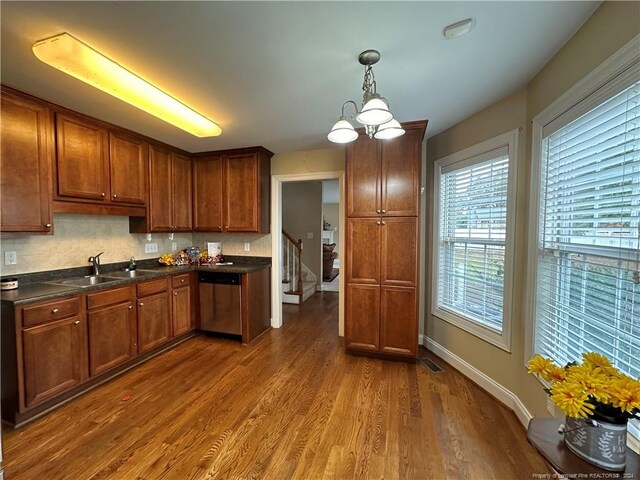 kitchen featuring tasteful backsplash, decorative light fixtures, sink, dark wood-type flooring, and stainless steel dishwasher