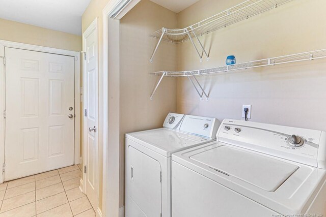 clothes washing area featuring washing machine and dryer and light tile patterned floors