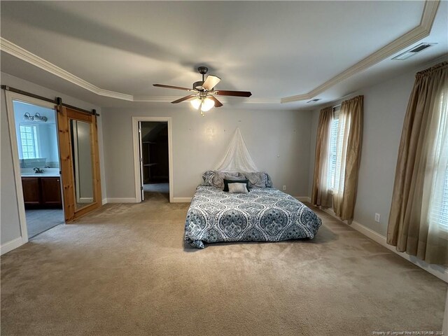 carpeted bedroom with ensuite bathroom, multiple windows, a barn door, and ceiling fan