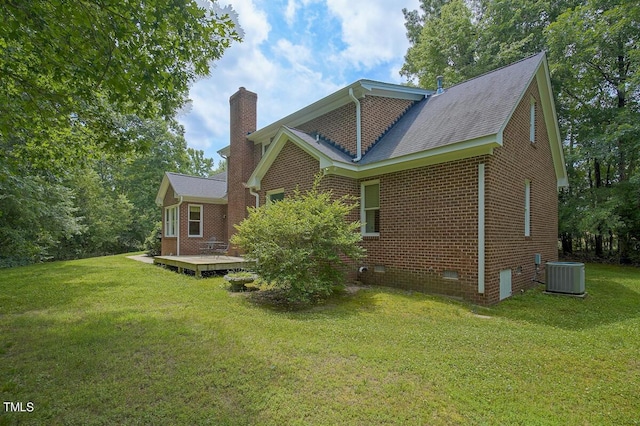 rear view of house with central AC unit, a wooden deck, and a lawn