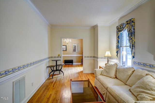 living room with a chandelier, light hardwood / wood-style floors, and ornamental molding