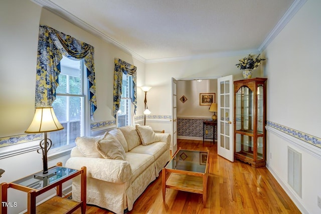 living room with french doors, crown molding, and light hardwood / wood-style flooring